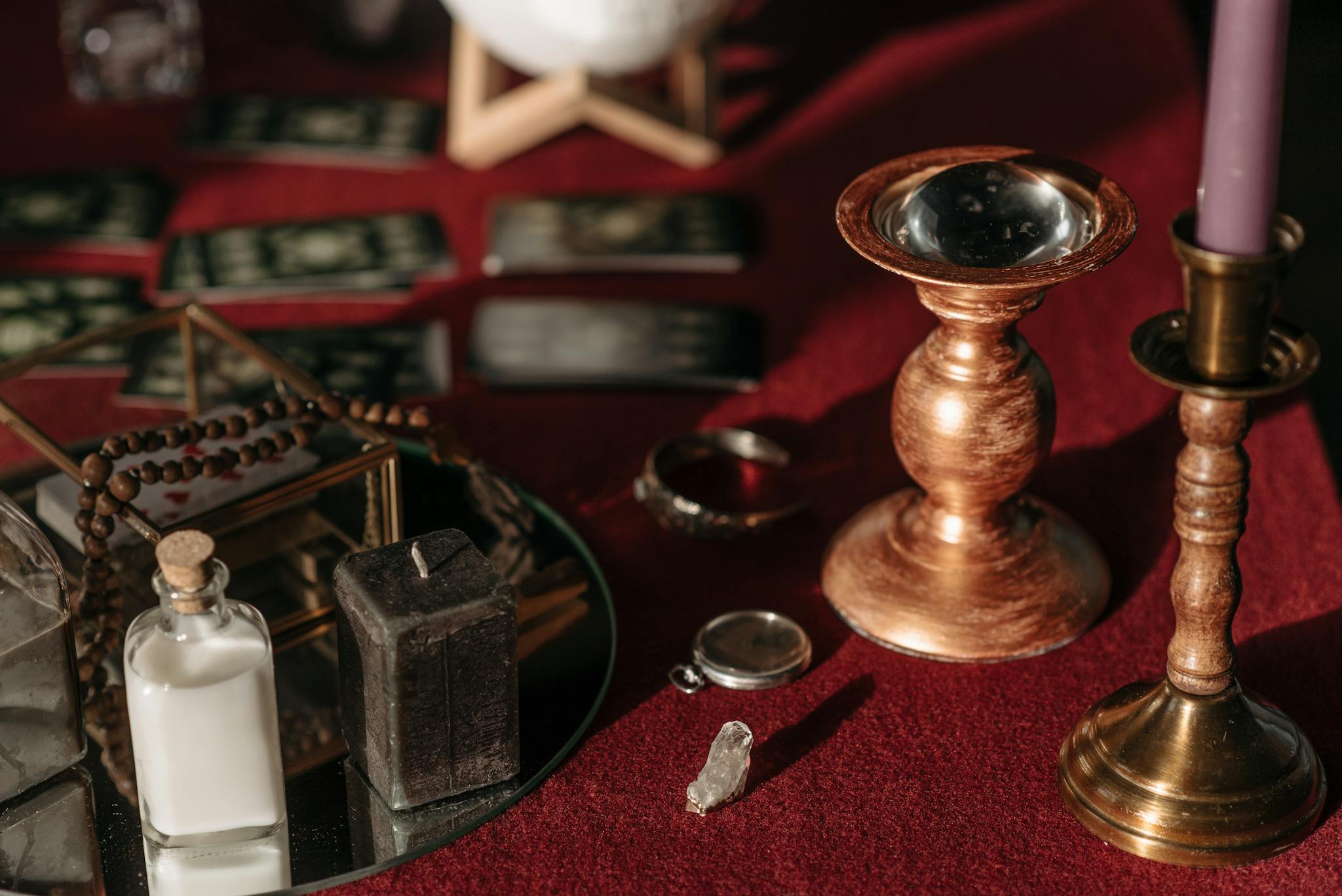 Vintage fortune telling arrangement featuring candles, tarot cards, and mystical items on a red table.